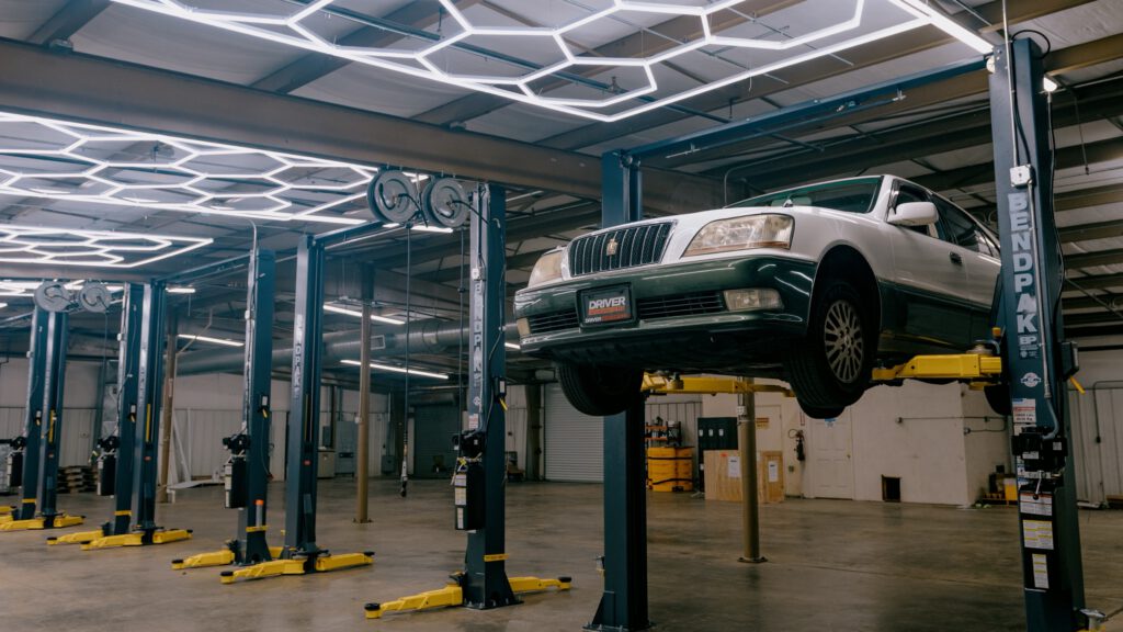A sedan raised on a two-post lift in one of the service bays