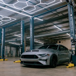 A silver Mustang parked in a service bay between BendPak lifts