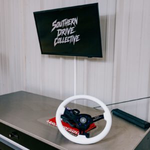 A white steering wheel on a tool chest under a Southern Drive Collective screen