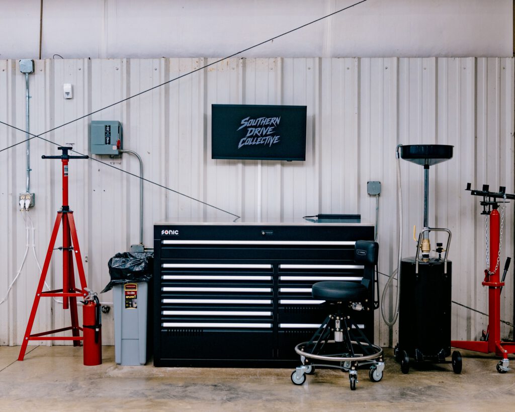 A service bay workstation: Sonic tool chest, mechanic's stool, jack stands and an oil drain